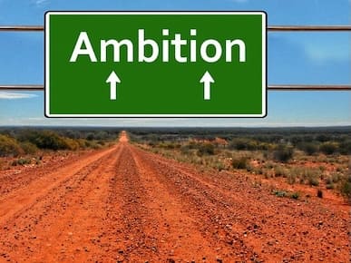 A picture of a road sign ahead saying, 'Ambition'.