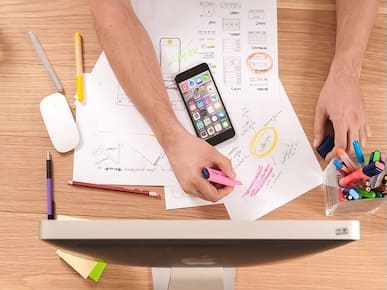 A picture of a workstation with blueprints to software UX/UI.