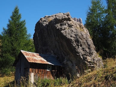 A picture of a big rock leaning on a small house.